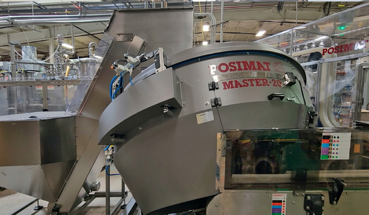 POSIMAT gravity bottle unscrambler installed in a filling line, providing high-speed bottle handling with reduced maintenance requirements.