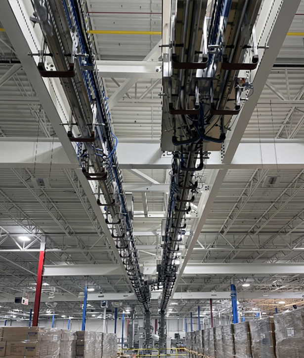 Overhead POSIJET air conveyor transporting PET bottles through a high-speed bottling facility, improving production flow and operational efficiency.