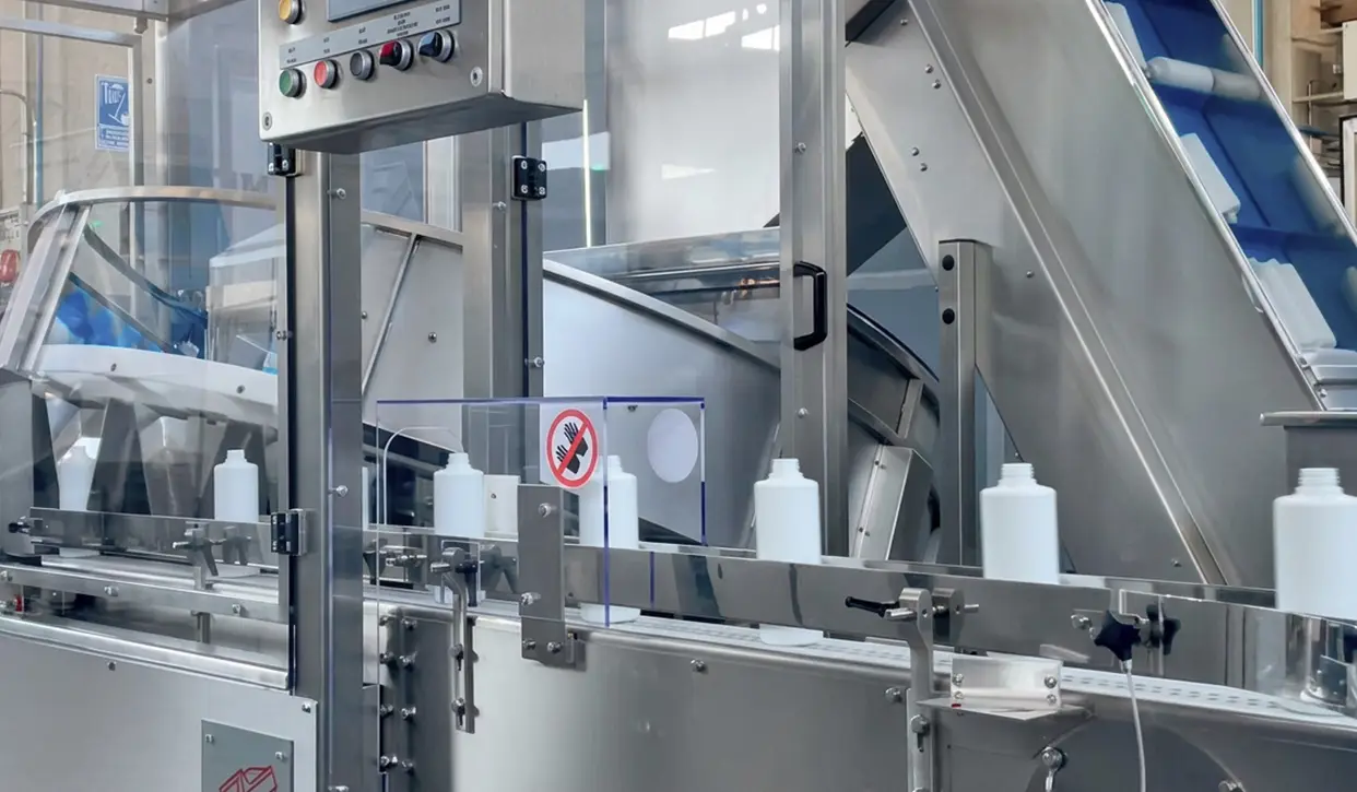 Front view of a POSIMAT bottle unscrambler for automated empty bottle handling in a pharmaceutical filling line.