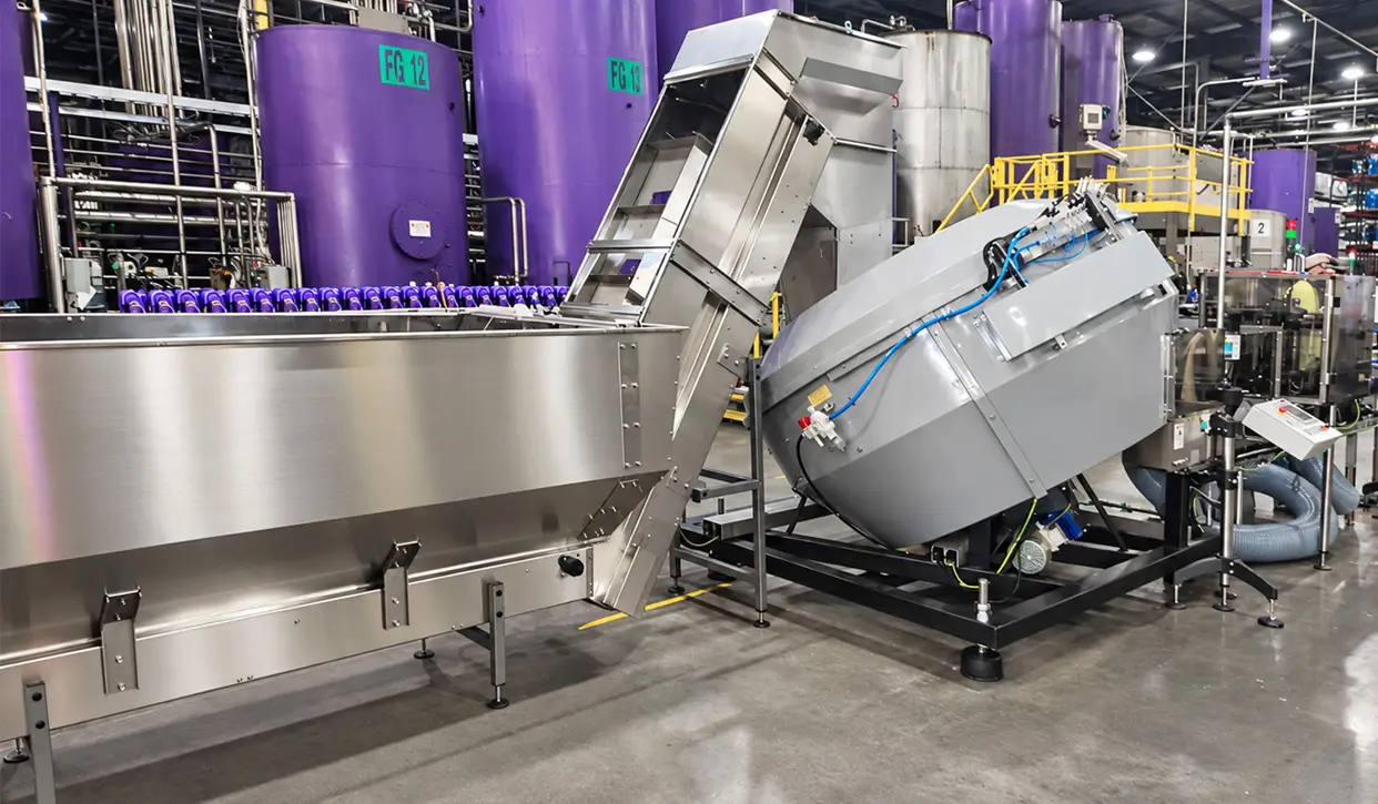 POSIMAT bottle unscrambler with hopper and elevator for automated feeding of plastic bottles into a lubricant bottling line.