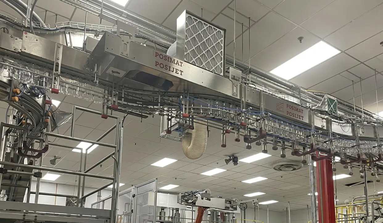 Overhead POSIJET air conveyor transporting PET bottles through a high-speed manufacturing line for efficient empty bottle handling.