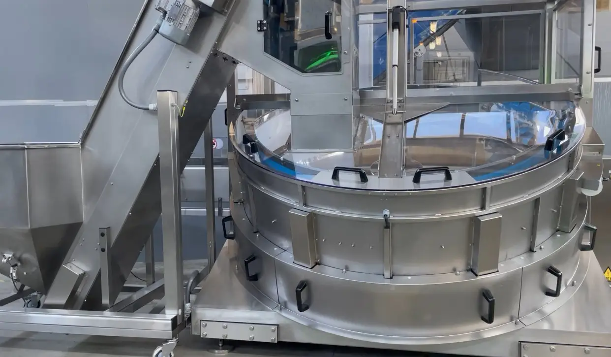 Rear view of a POSIMAT bottle unscrambler for automated empty bottle handling in a pharmaceutical filling line.