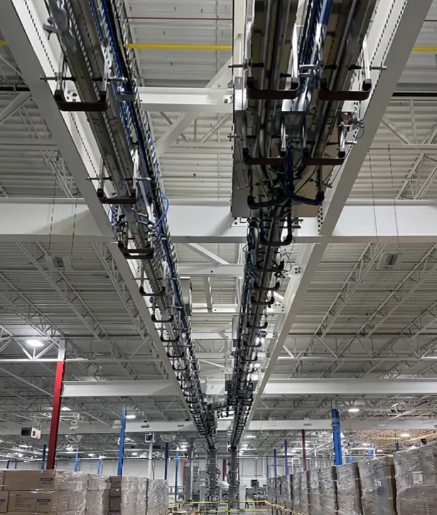 Overhead POSIJET air conveyor transporting PET bottles through a high-speed bottling facility, improving production flow and operational efficiency.