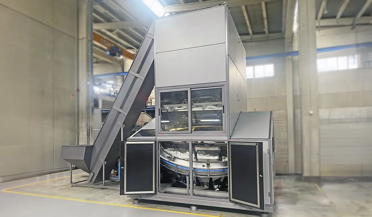 POSIMAT bottle unscrambler with open access doors, showing the rotary bottle handling system, overhead storage silo and inclined elevator for automatic bottle feeding.